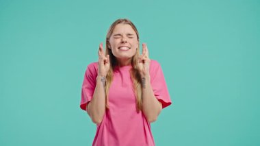 Mavi stüdyo arka planında dua eden hoş bir kadın. Vücut pozitifliği olan kadın, birine arzularını tatmin etmesi için yalvarır, yardım eder, şans için dua eder. Yüksek kalite 4k