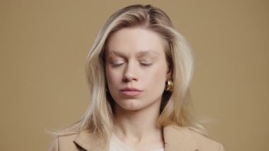 Ciddi bir kadın baş işareti olmadan onaylamıyor, onaylanmayacak şekilde başını sallıyor. Reddetmek, reddetmek, anlaşmazlık bej arka planda güzel bir bayanın portresi. Yüksek kalite 4k görüntü