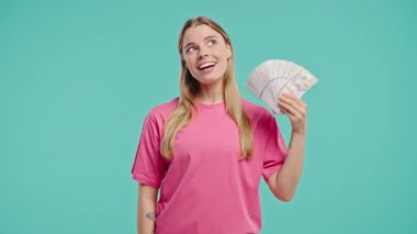 Nakit parası olan zengin, heyecanlı bir kadın. Blue Wall 'da Amerikan Doları banknotları. İkramiye, kazanç, zafer, kazanan piyango, maaş sembolü. Yüksek kalite 4k 