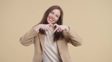 Gülümseyen güzel kadın kalp şeklinde. Bej renkli olumlu kadın. Sevgi. Kadın sağlığı, gönüllülük, bağış, minnettarlık sembolü, flört konsepti. Yüksek kalite 4k görüntü