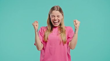 Kendine güvenen sarışın kadın başarısını enerjik bir yumruk pompası ve ışıltılı bir gülümsemeyle kutluyor. Başarı, duygusal kazanç, motivasyon, ilerleme, kadın gücü