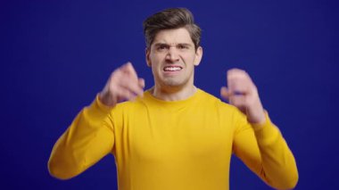 Sarılı sinirli adam şok olmuş bir ifadeyle kameraya bağırıyor. Baskı altındaki adam kötü habere, iş başarısızlığına ya da ofisteki stresli duruma tepki veriyor..