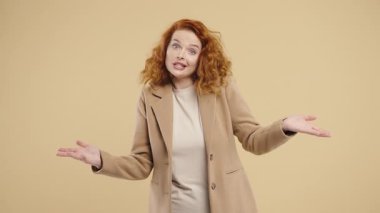 30 'lu yaşlarda güzel bir kadın. Omuzları yukarıda. Yardımcı olamıyor. Zor soru, suçlu tepkisi, bej arka planda. Yüksek kalite 4k