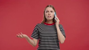 Sinirli genç bir kadın cep telefonuyla konuşurken kavga ediyor. Stresli kızgın bir kadın. Kırmızı stüdyo geçmişi. Çatışma, anlaşmazlık, olumsuz. Yüksek kalite 4k görüntü