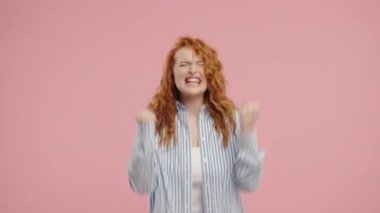 Kendine güvenen kızıl saçlı kadın başarıyı enerjik bir yumruk pompası ve ışıltılı bir gülümsemeyle kutluyor. Başarı, duygusal kazanç, motivasyon, ilerleme, kadın gücü