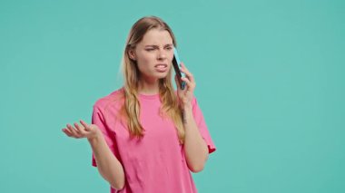 Sinirli genç bir kadın cep telefonuyla konuşurken kavga ediyor. Stresli kızgın bir kadın. Mavi stüdyo geçmişi. Çatışma, anlaşmazlık, olumsuz. Yüksek kalite 4k görüntü