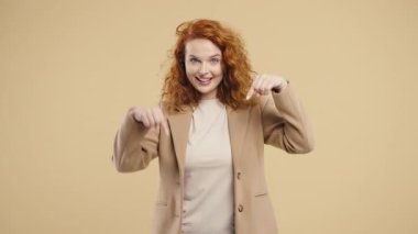 Genç kadın blogcu reklam alanını işaret ediyor. Bej arka plan. Güzel bayan aşağıya üye olmak için tıklamak istiyor. Ticari fikir ve tanıtım içeriği için kopyalama alanı. Yüksek kalite 4k