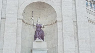 Roma, İtalya - 25 Eylül 2025. Klasik Minerva, Roma bilgelik ve savaş tanrıçası. Bu figür bir mızrak tutuyor ve miğfer takıyor, tarihi mimari ortamda güç ve zarafet simgeliyor..