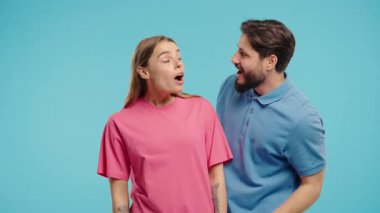 Dedikoducu adam kadınların kulağına fısıldıyor. Dedikodular, dedikodular, mavi stüdyo. Güzel bayan ve yakışıklı adam. Komplo konsepti. Yüksek kalite 4k görüntü