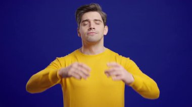 Sakin adam dinleniyor, meditasyon yapıyor. Yakışıklı Avrupalı adam sakinleşiyor, Mudra om ile derin derin nefes alıyor. Stüdyo görüntüleri. Yüksek kalite 4k görüntü