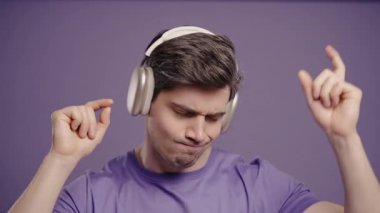 Violet Stüdyosunda Kulaklıkla Dans Eden Aktif Genç Adam. Mutlu adam, harika ruh hali. Yüksek kalite 4k görüntü