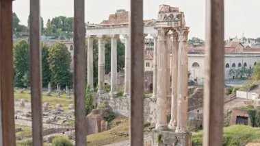 Roma Forumu 'nun geniş manzarasında antik kalıntılar, taş sütunlar, sıcak güneş ışığıyla yıkanmış tarihi yerler sergileniyor. Turistler ikonik arkeolojik alanı keşfediyorlar
