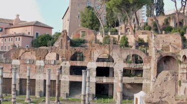 Roma Forumu 'nun geniş manzarasında antik kalıntılar, taş sütunlar, sıcak güneş ışığıyla yıkanmış tarihi yerler sergileniyor. Turistler ikonik arkeolojik alanı keşfediyorlar