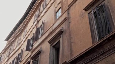 Klasik Roma yerleşim cephesi Pastel duvarları, geleneksel ahşap panjurlar. Eski duvarcılık ve günlük Roma yaşamının cazibesi.