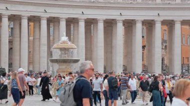Vatikan, Roma - 25 Eylül 2025. Vatikan 'daki St. Peters Meydanı yürüyen, fotoğraf çeken ve büyük sütunlara hayran olan turistlerle dolu. Bazilika klasik bir editoryal seyahat sahnesi yarattı.