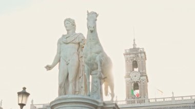 Roma Capitoline Tepesi 'nde atıyla birlikte antik mermer Castor heykeli. Yumuşak gün ışığı klasik heykelin detaylarını gözler önüne sererken, Palazzo Senatorio arkasında yükselerek ikonik Roma mirası sergiliyor..