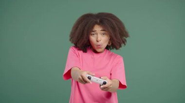 Güzel genç bir kadın TV 'de oyun oynuyor. Oyun kolu yeşil stüdyo arka planında izole edilmiş. Modern teknolojiyi kullanarak. E-spor, hobi, akış