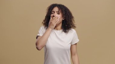 Bej rengi stüdyo arka planında esnemekten yorulmuş genç bir kadın. Tembel genç kız yeterince uyuyamadı. Yüksek kalite 4k görüntü