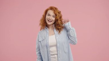 Dost canlısı genç Amerikalı kadın el sallıyor - merhaba, ya da selam, kao, adios. Ayrılıyorum, kameraya hoşça kal de. Pembe stüdyo geçmişinde güzel bir bayan. Yüksek kalite 4k