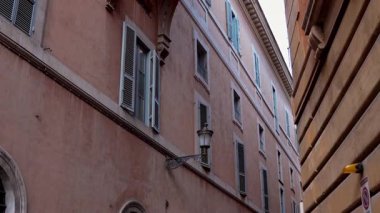 Popüler seyahat yeri. Yürüyen kişinin öznel sabit görüntüsü. Pastel duvarları olan klasik Roma yerleşim cephesi. Günlük Roma yaşamının eski duvar ustalığı ve cazibesi.