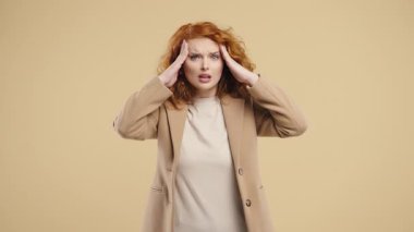 Baş ağrısı, kan basıncı, stüdyo fotoğrafı olan genç bir kadın. Kız ellerini başının üstüne koyuyor, bej arka planda izole edilmiş. Sorun kavramı, ilaç, hastalık. Yüksek kalite 4k