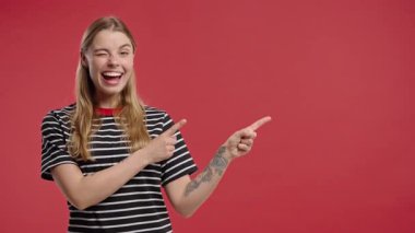 Gülümseyen 30 'lu yaşlardaki kadın reklam için boş bir yer arıyor. Önerilen kadın sağ tarafı işaret ediyor, boşluğu kopyalayın. Kadın, kırmızı arka planda izole edilmiş bir şey sunuyor. Yüksek kalite 4k