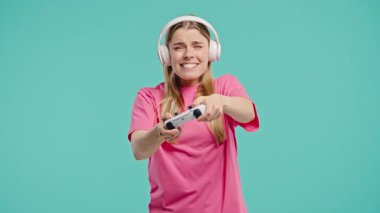 Televizyonda video oyunu oynayan genç ve güzel bir kadın mavi stüdyo arka planında joystick izole edilmiş. Modern teknolojiyi kullanarak. E-spor, hobi, akış