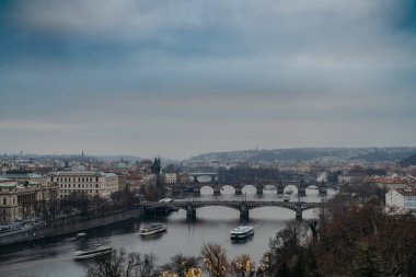 Prag, Çek Cumhuriyeti - 20 Aralık 2025. Vltava Nehri 'ne bakan Letna bakış açısından su boyunca sorunsuz hareket eden teknelere bakın. Şehir ritmi, ikonik köprüler, panoramik şehir manzarası, seyahat, turizm