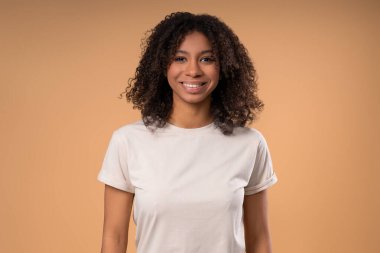 Şık liseli kız, doğal gerçek güzellik. Genç bayan kameraya gülümseyerek bakıyor. Sağlıklı cilt ve dişler. Afrikalı kıvırcık saçlı melez bir kadın, Z jenerasyonunda otantik bir kadın model..