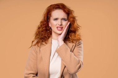 Bej renkli stüdyo geçmişinde diş ağrısı olan zeki bir kız öğrenci. Diş ağrısı, diş sorunları, diş hekimliği ve ilaç konsepti. Yüksek kalite fotoğraf