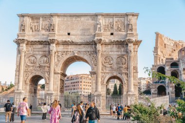 Roma, İtalya - 25 Eylül 2025. Konstantin Kemeri, turistler güneşli bir günde tarihi anıtın etrafında yürürken Kolezyum yakınlarında duruyor. Antik Roma zafer kemeri ünlü bir simgedir.