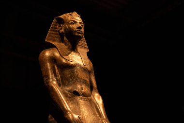 Eski Mısır firavunu heykeli müzede koyu arka planda sergileniyordu. Heykel, geleneksel Nemes başlığı takan kraliyet figürünü gösteriyor, gücün ve kutsallığın sembolü..