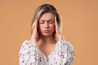 Baş ağrısı, kan basıncı, stüdyo portresi olan çekici bir kadın. Kafasında elleri olan bir kadın, izole edilmiş bej bir geçmişi var. Sorunlar, migren semptomları, hastalık. Yüksek kalite fotoğraf