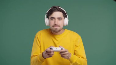 Televizyonda video oyunu oynayan yakışıklı esmer adam. Oyun kolu yeşil stüdyo arka planında izole edilmiş. Modern teknolojiyi kullanarak. Yüksek kalite 4k görüntü