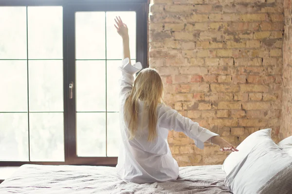 Frau streckt sich nach dem Aufwachen im Bett — Stockfoto
