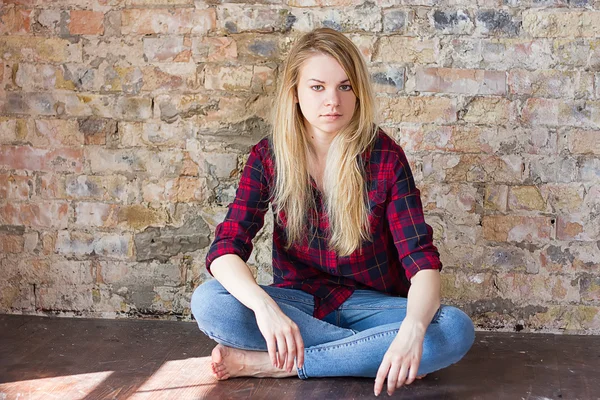 Čelní pohled atraktivní bílé dívky, sedící na dřevěnou podlahu — Stock fotografie
