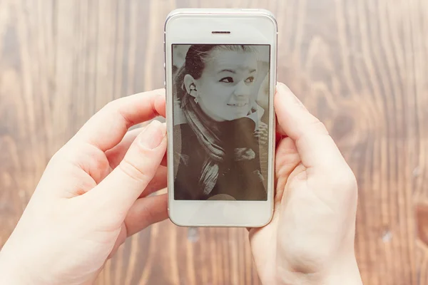 Dívka vypadá na telefon s její fotografií — Stock fotografie