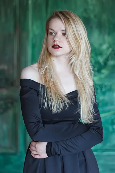 Elegante Blondine im schwarzen Kleid in der Nähe der Grunge-Wand — Stockfoto