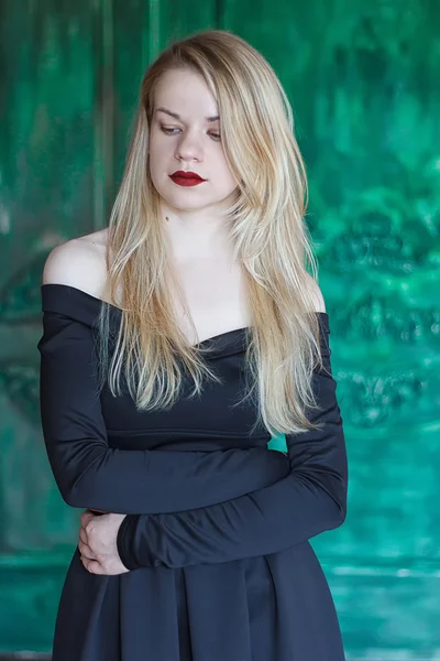 Elegante bionda in un abito nero vicino alla parete grunge — Foto Stock