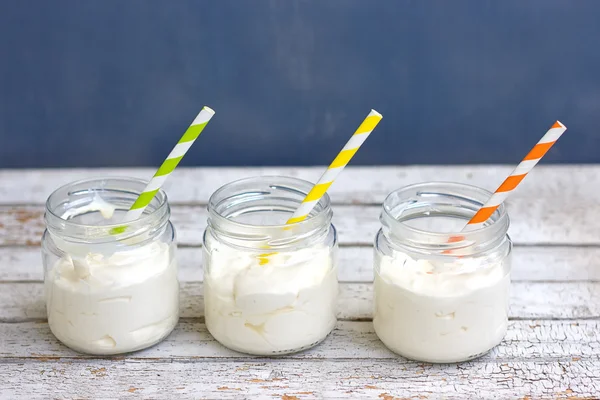 Yogurt dalam tiga guci kecil dengan sedotan. Pada papan putih — Stok Foto