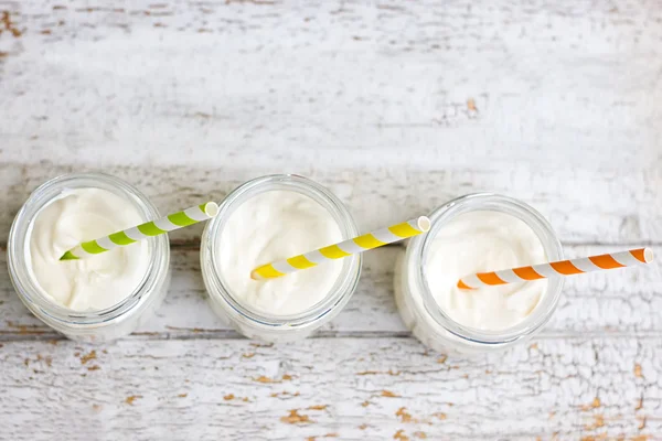 Yogurt in three small jars with straws — Stock Photo, Image