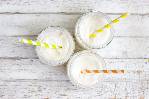 Jogurt ve třech malých sklenicích s brčka — Stock fotografie