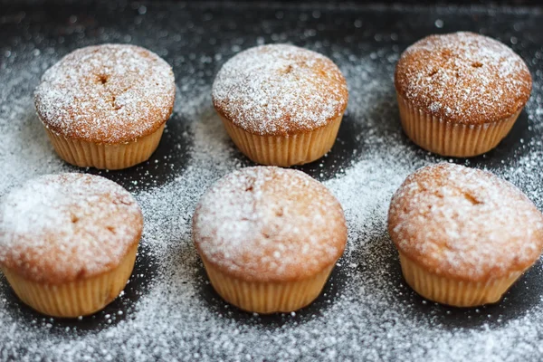 Muffins in poedersuiker op een donker — Stockfoto