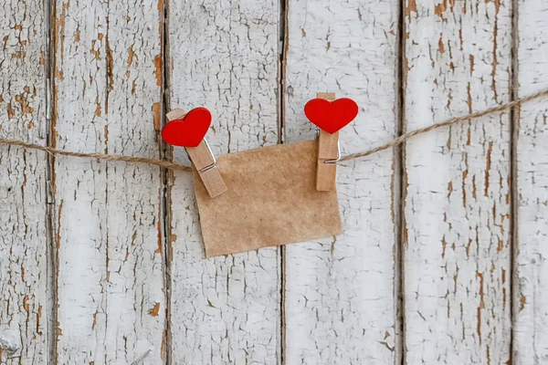 Note on the background of an old fence with clothespins in heart shape — Stock Photo, Image