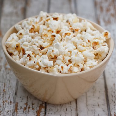 Beyaz ahşap masa üzerinde kase taze patlamış mısır