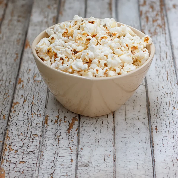 Fresh popcorn in bowl on white wooden table — Stock Photo, Image