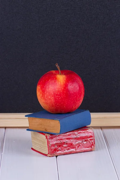 Kırmızı elma yazı tahtası karşı eski mini kitap — Stok fotoğraf