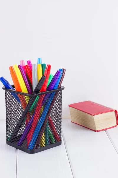 Marcadores multicoloridos no estande ao lado de pequenos livros — Fotografia de Stock