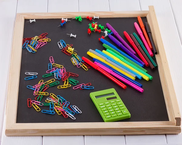 calculator, paper clips, markers on black Board