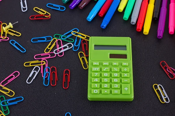 Taschenrechner, Büroklammern, Filzstifte auf schwarzer Tafel — Stockfoto